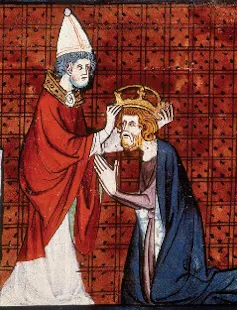 An illustration shows one man in a pointed hat putting a crown on a kneeling man's head, set against a red background.
