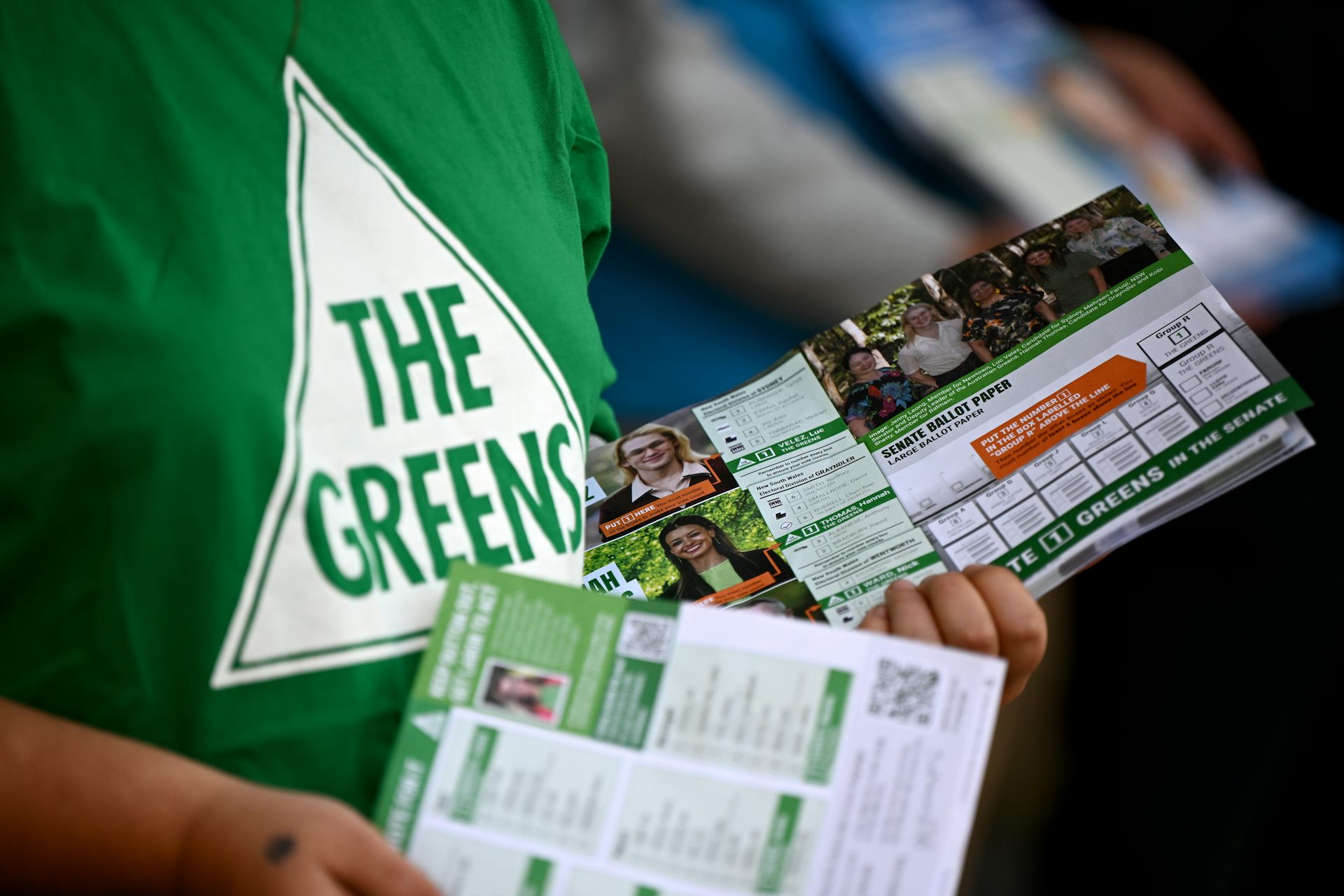 A Greens t-shirt and hands holding political pamphlets.