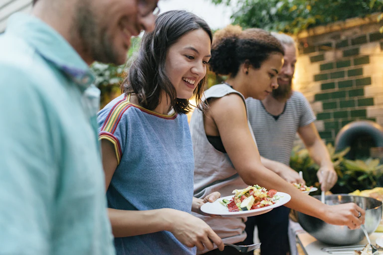 Friends at a barbequeue fill their plates with food.