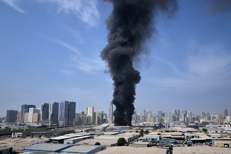 Black smoke against blue sky and cityscape.