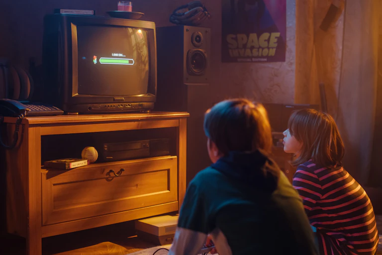 Two children playing video games on an old television set.