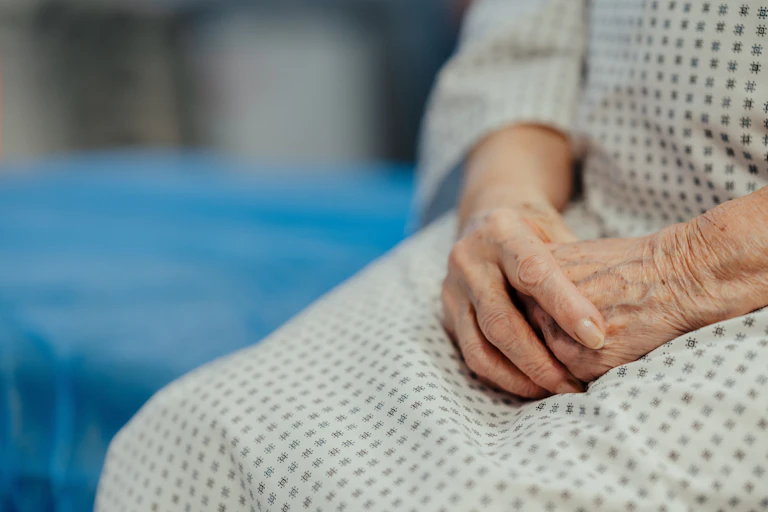 Close up of hands of senior patient on examination table in the hospital.