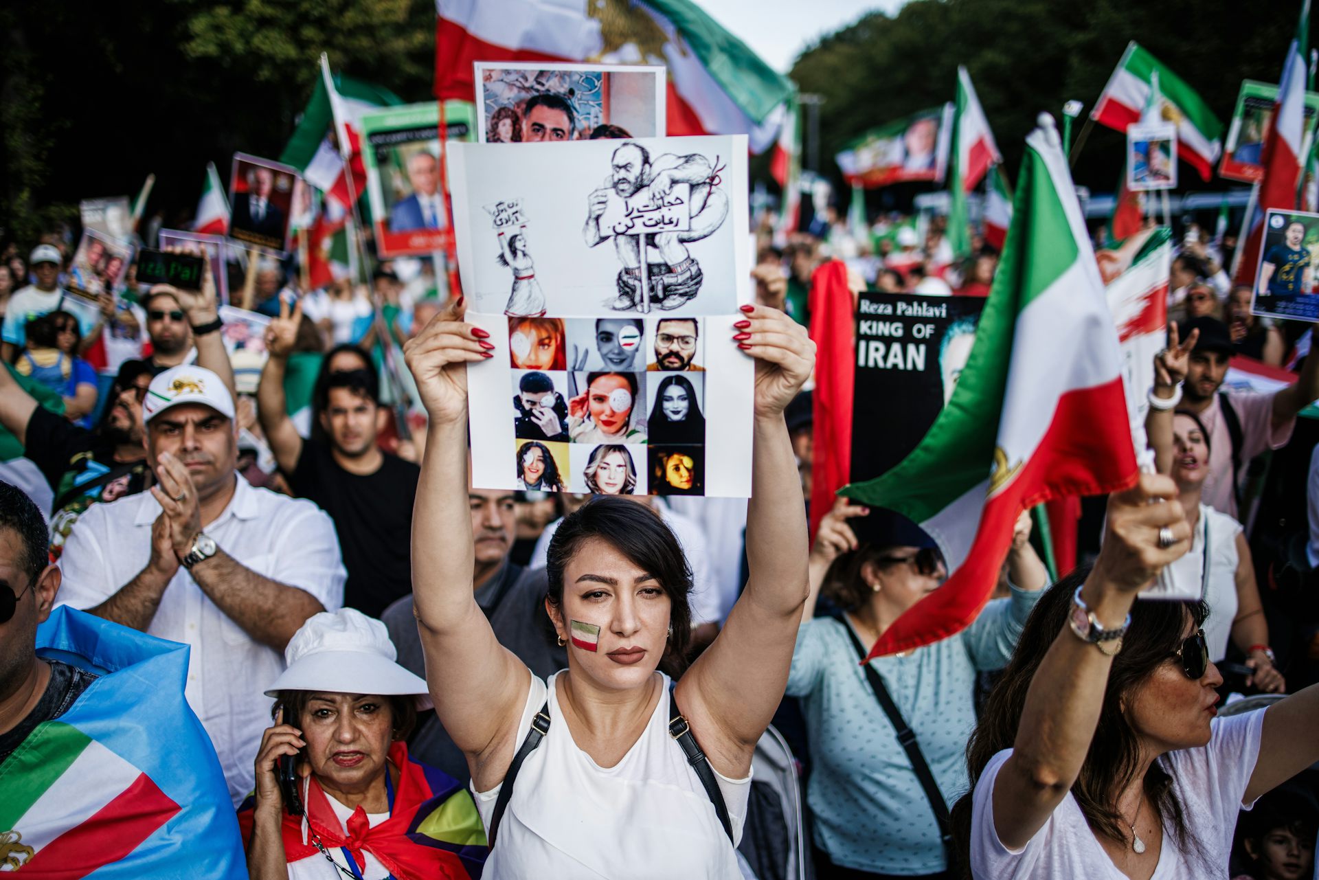 A demonstrator holds a sheet showing photos of victims at the anniversary of the death of Mahsa Jina Amini in 2023.