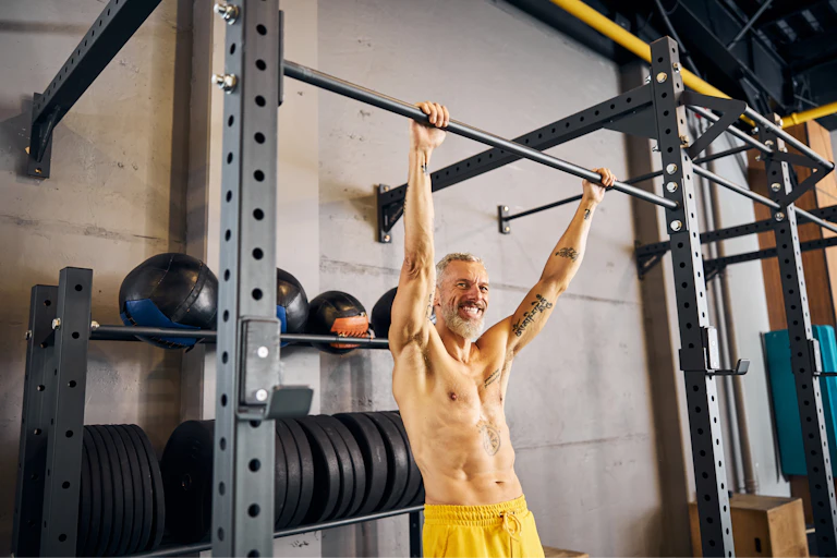 Cheerful man grabs the chin-up bar with both hands before performing the dead hang exercise