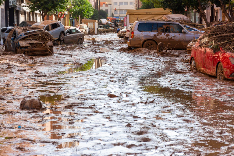 wrecked cars in a sludgy street in the aftermath of the valencia floods in 2024.