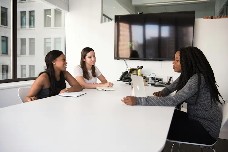 Three people at a table in discussion.