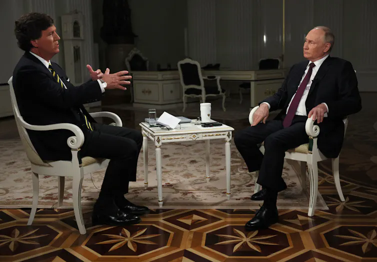 two suited men on chairs talking