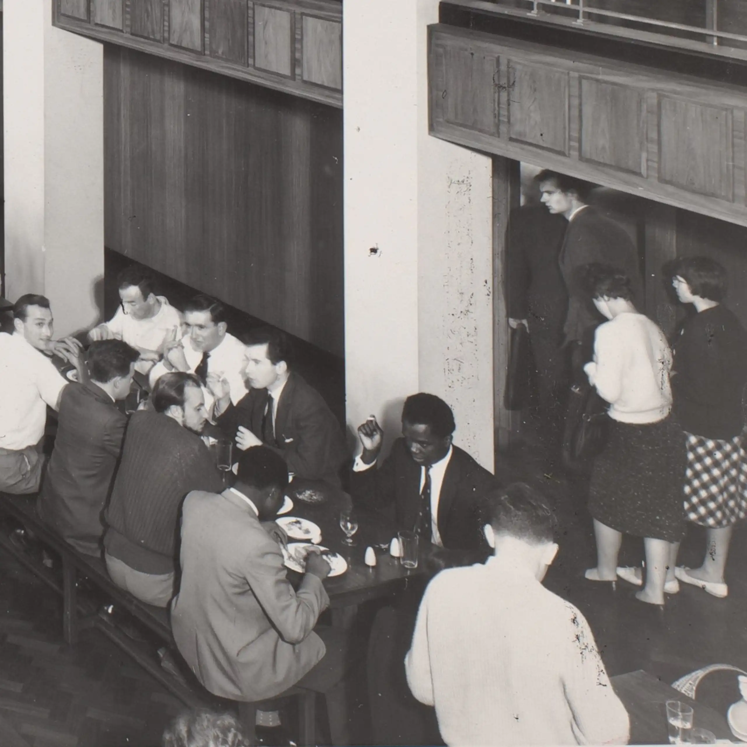 A black and white image of students eating a meal together in a university refectory in the 1960s