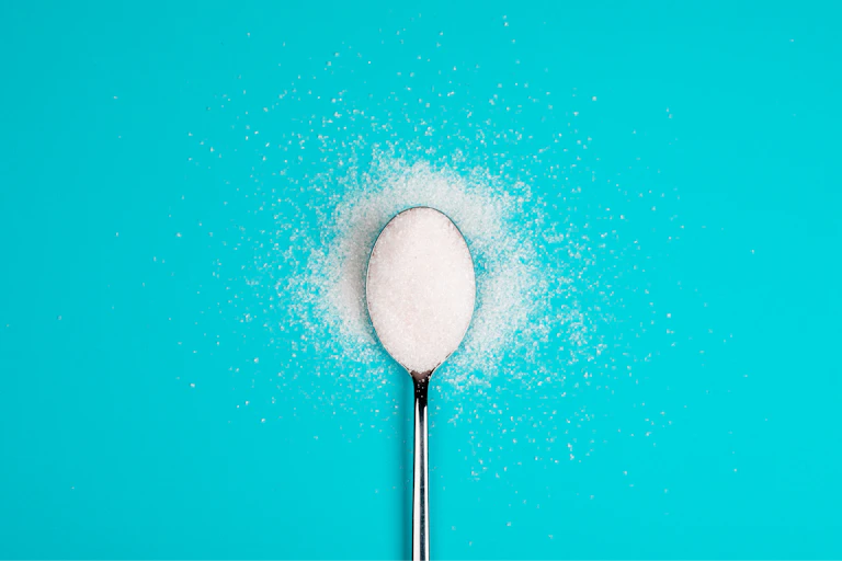 Spoonful of sweetener against a blue background
