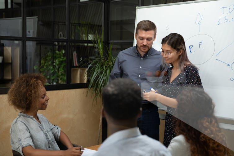Mientras el gobierno de EE. UU. investiga fenómenos anómalos no identificados, los investigadores académicos que los estudian enfrentan el estigma 1 Un grupo de cuatro personas trabajando juntas, dos de ellas paradas frente a una pizarra.