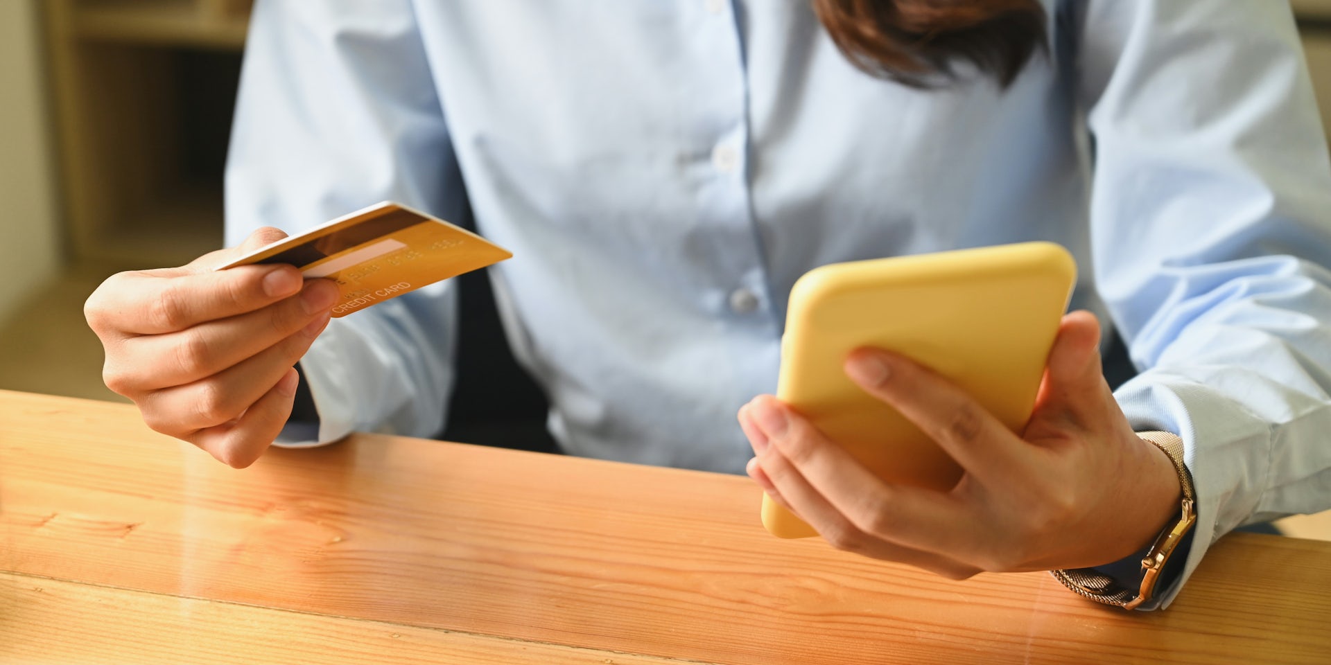 A person holds a bank card while inspecting a cell phone.