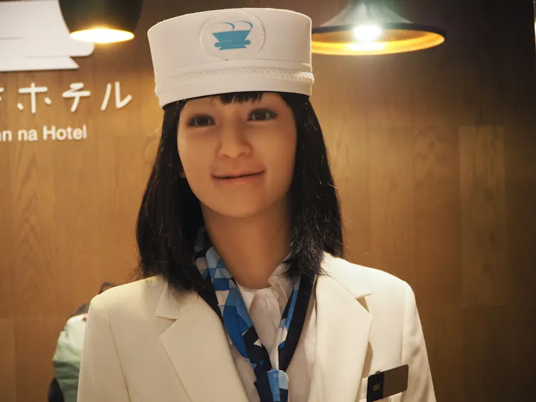 Un robot que se intenta parecer a una mujer de carne y hueso vestido de uniforme.