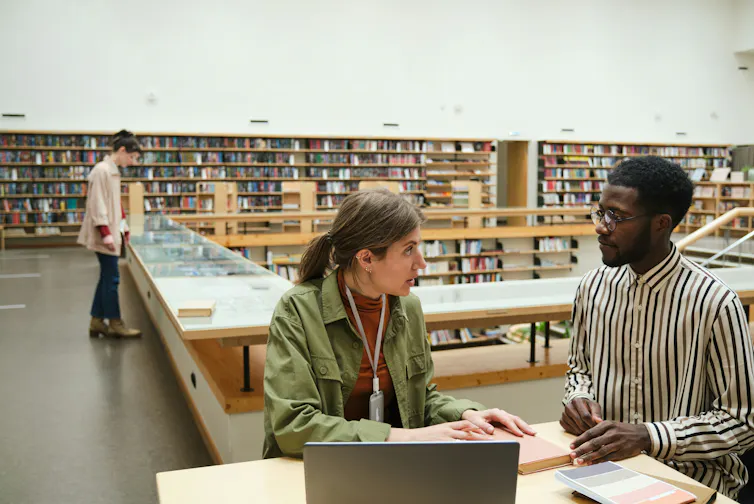 Two people in discussion at library stacks.