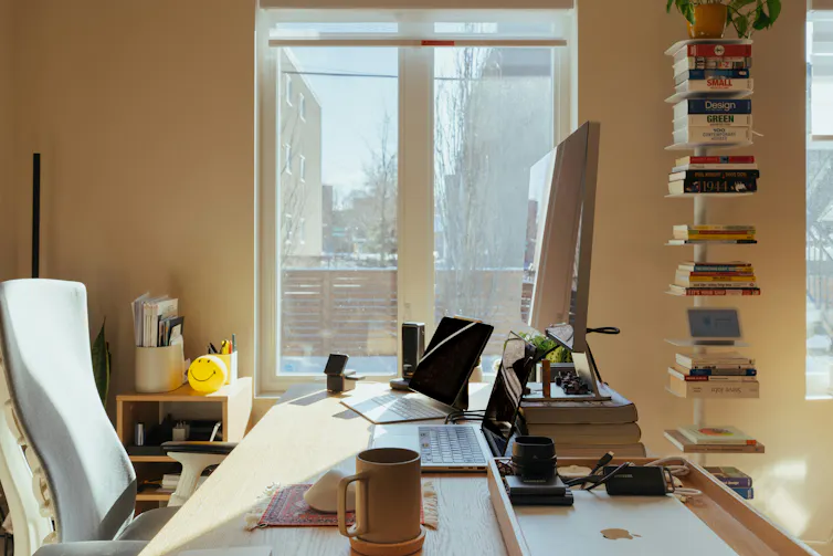 A workspace with a coffee cup, smiling bauble books and a computer.