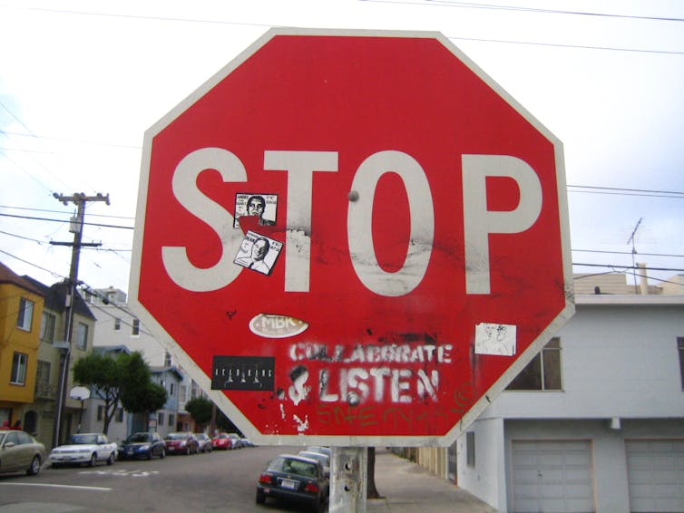 red stop sign with stickers and graffiti