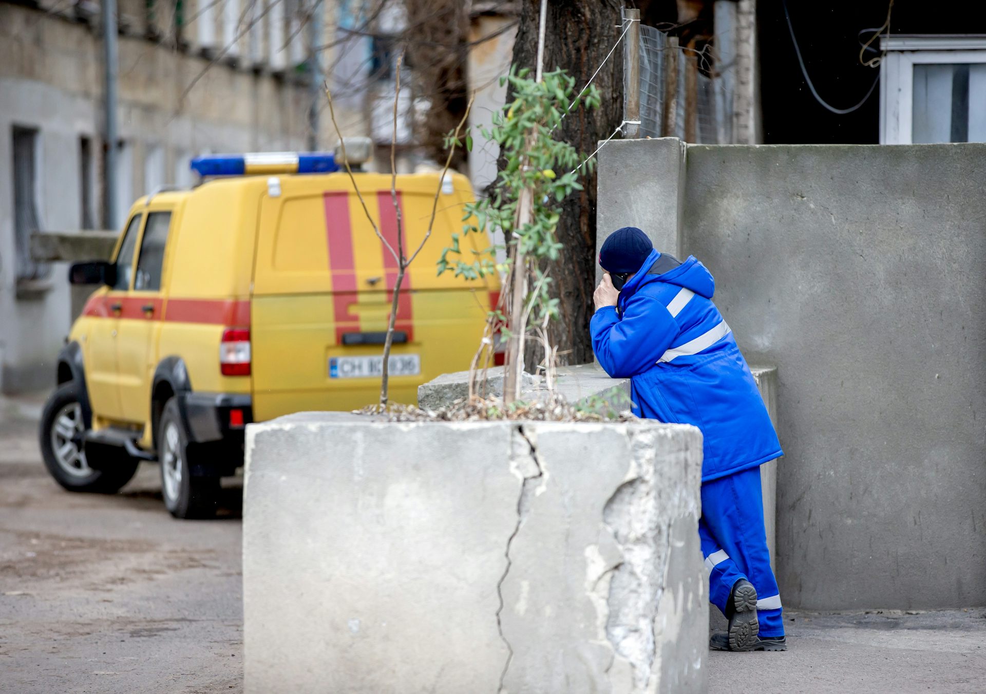 A gas worker in Chișinău, Moldova, stands next to his van on his phone.