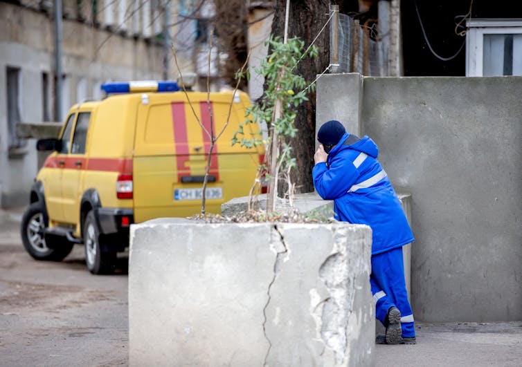 A gas worker in Chișinău, Moldova, stands next to his van on his phone.