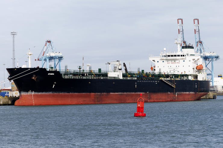 A large tanker ship sits alongside a pier.