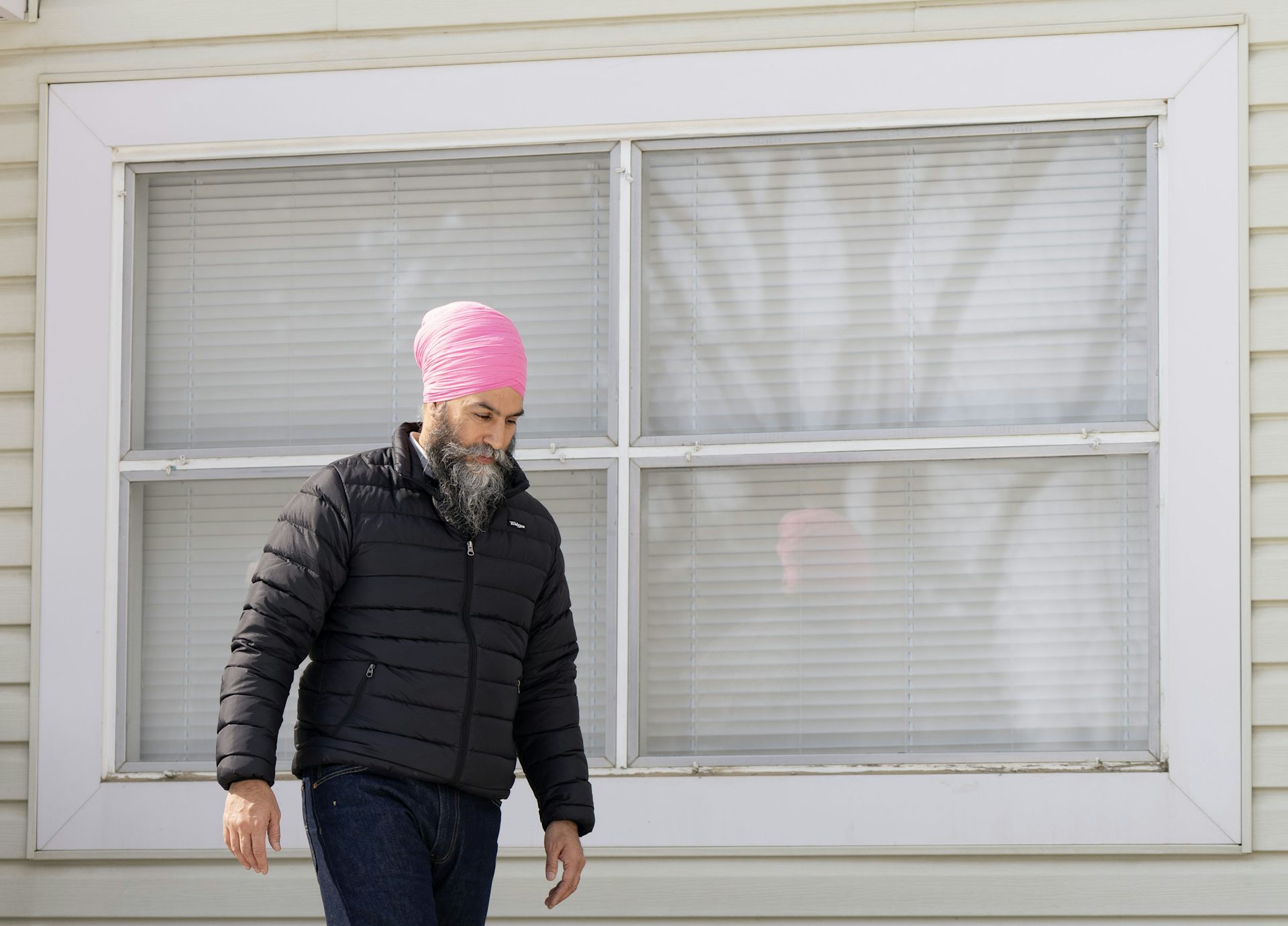 Un hombre barbudo y con un turbante rosa pasa por delante de la casa.