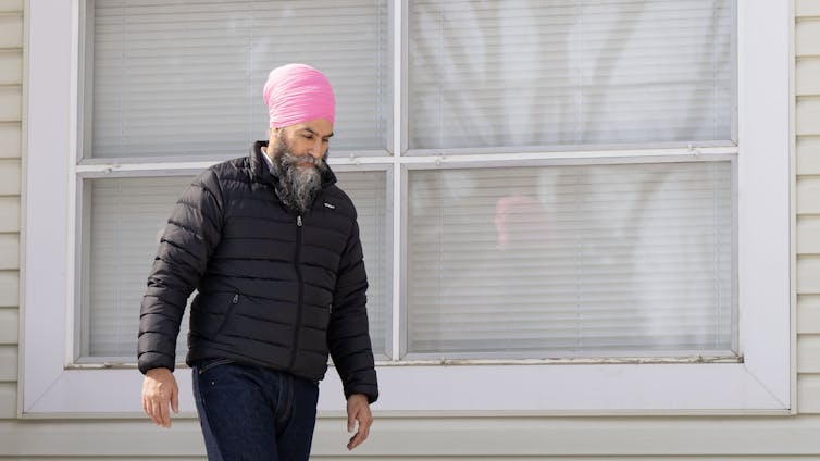 Un hombre barbudo y con un turbante rosa pasa por delante de la casa.