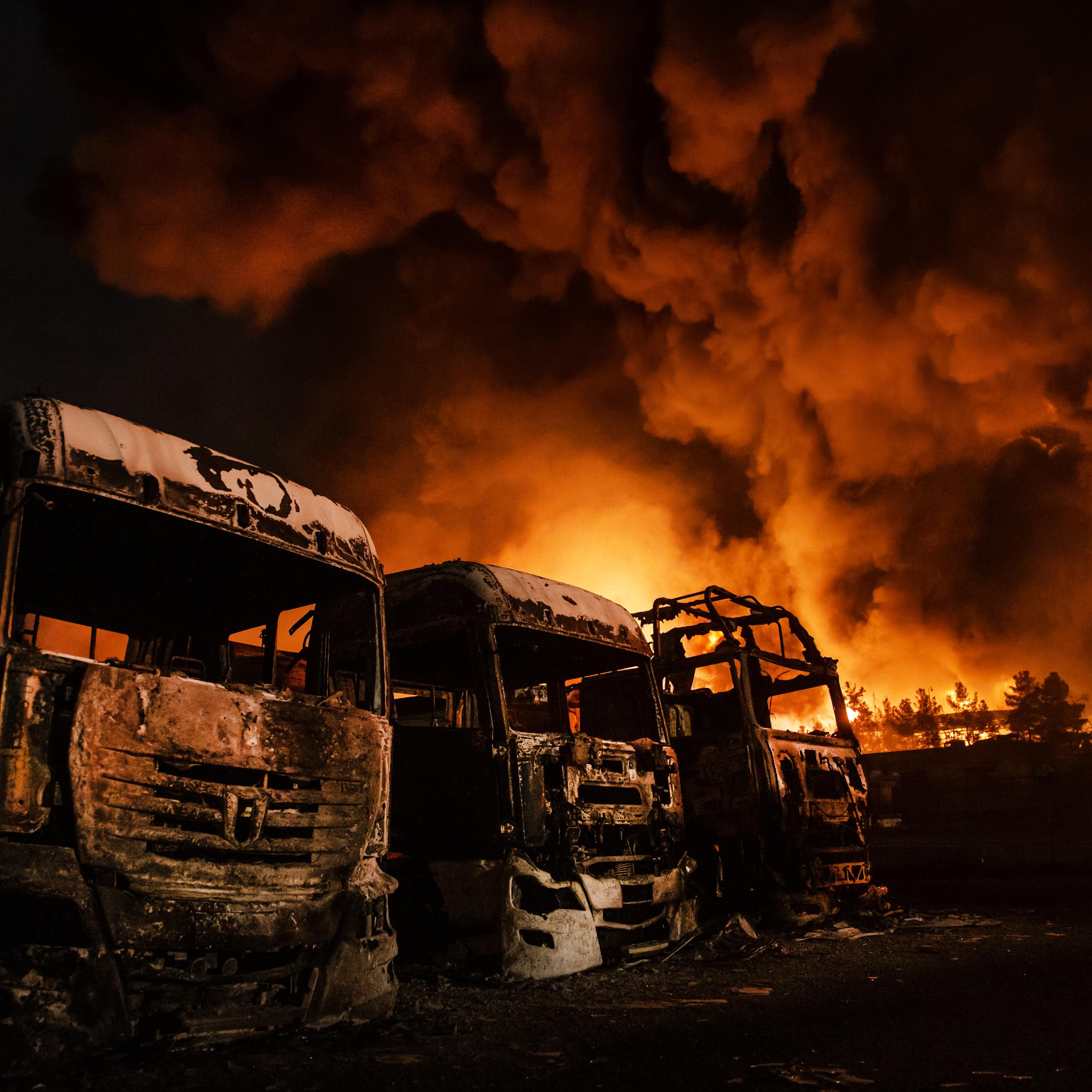 Fire rages behind burned-out buses.