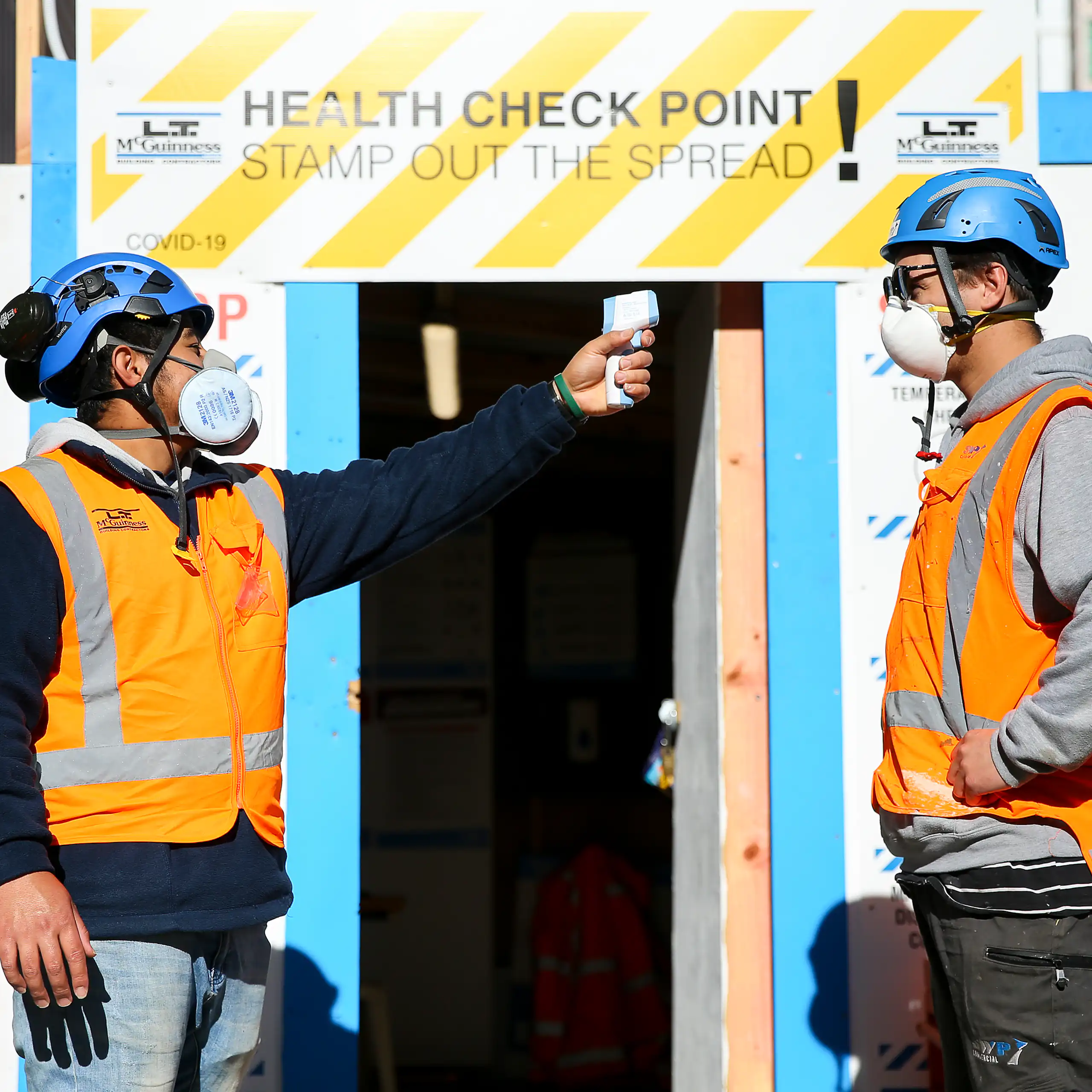A worker conducts a temperature check at the entrance of a construction site during the COVID pandemic.
