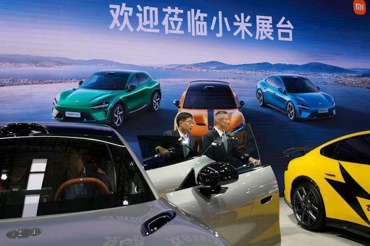 Visitors stand near electric cars in bright colours at the 2025 World Intelligent Connected Vehicles Conference in Beijing, China