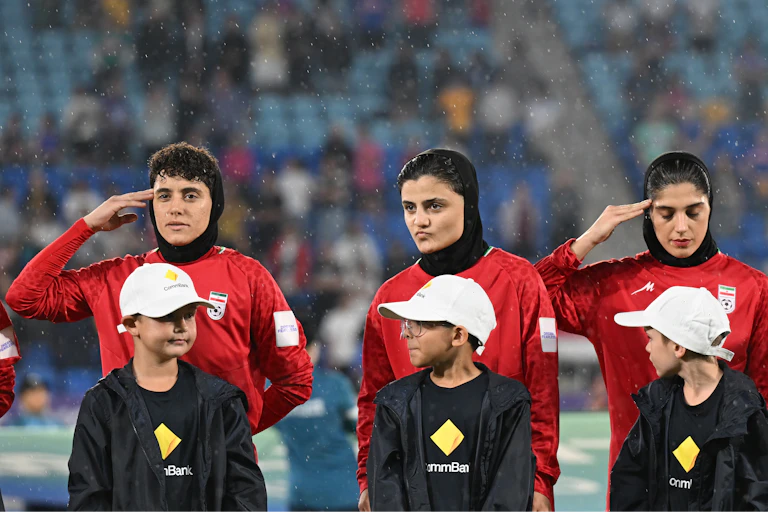 Some members of the Iran women's soccer team salute during the national anthem ahead of an Asian Women's Cup game.