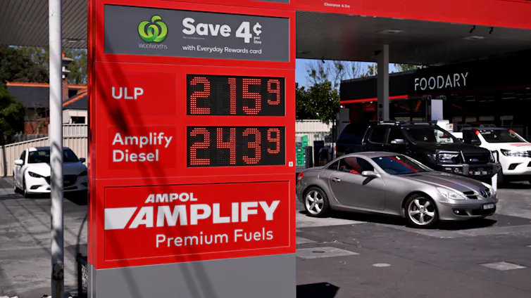 Cars buying fuel at a fuel station, prices seen on a digital display.