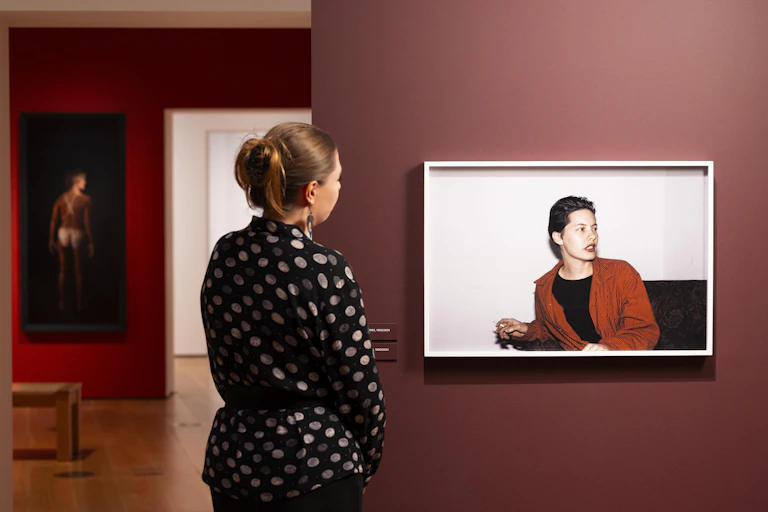 A woman looks at a portrait of a person in a red jacket