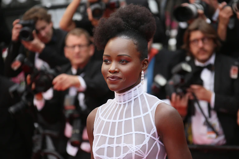 Actress Lupita Nyong'o poses for camera at a red carpet event.