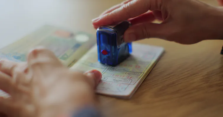 A hand putting a stamp into a passport