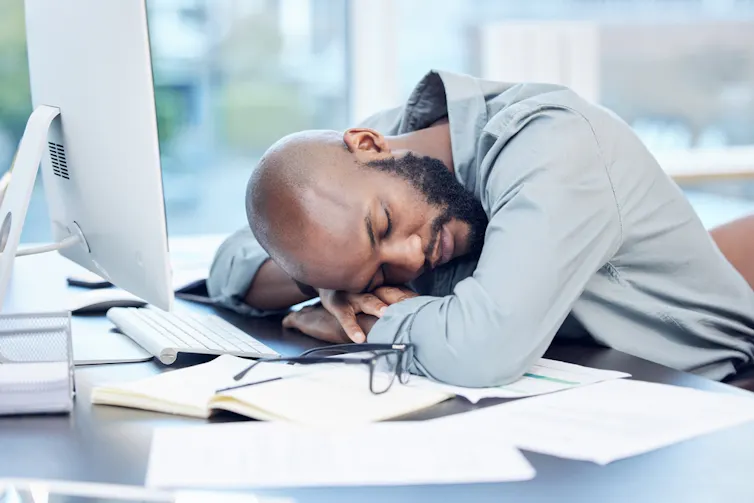 A tired employee sleeping at his desk.