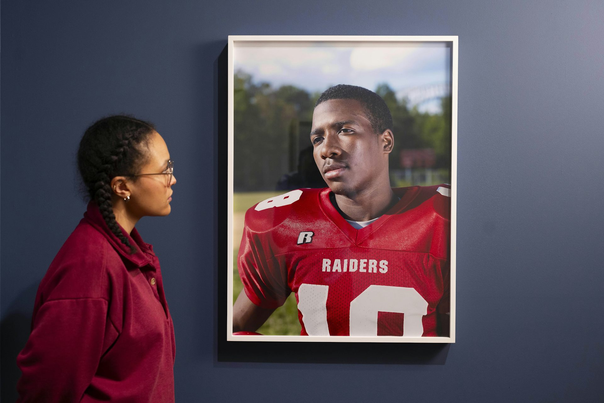 A woman looking at a portrait of an American football player.