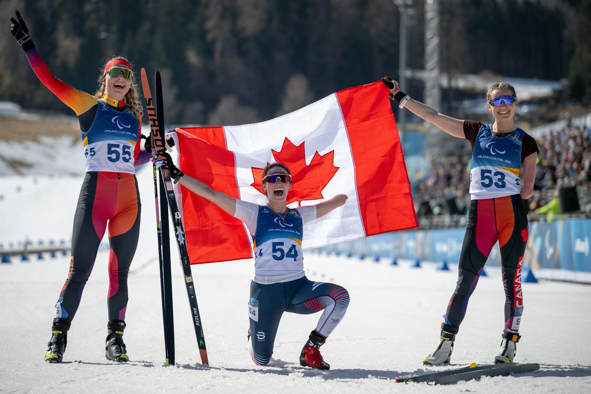 Tres atletas paralímpicos celebran la victoria y sostienen la bandera canadiense.