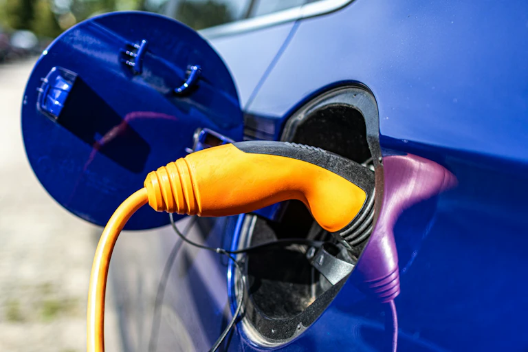 A close-up image of a yellow charging cord plugged into a blue electric car.