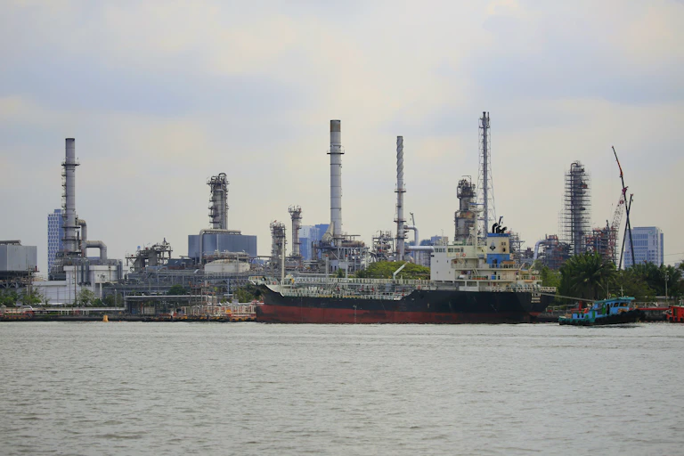 A large ship in the water with chimneys in the background