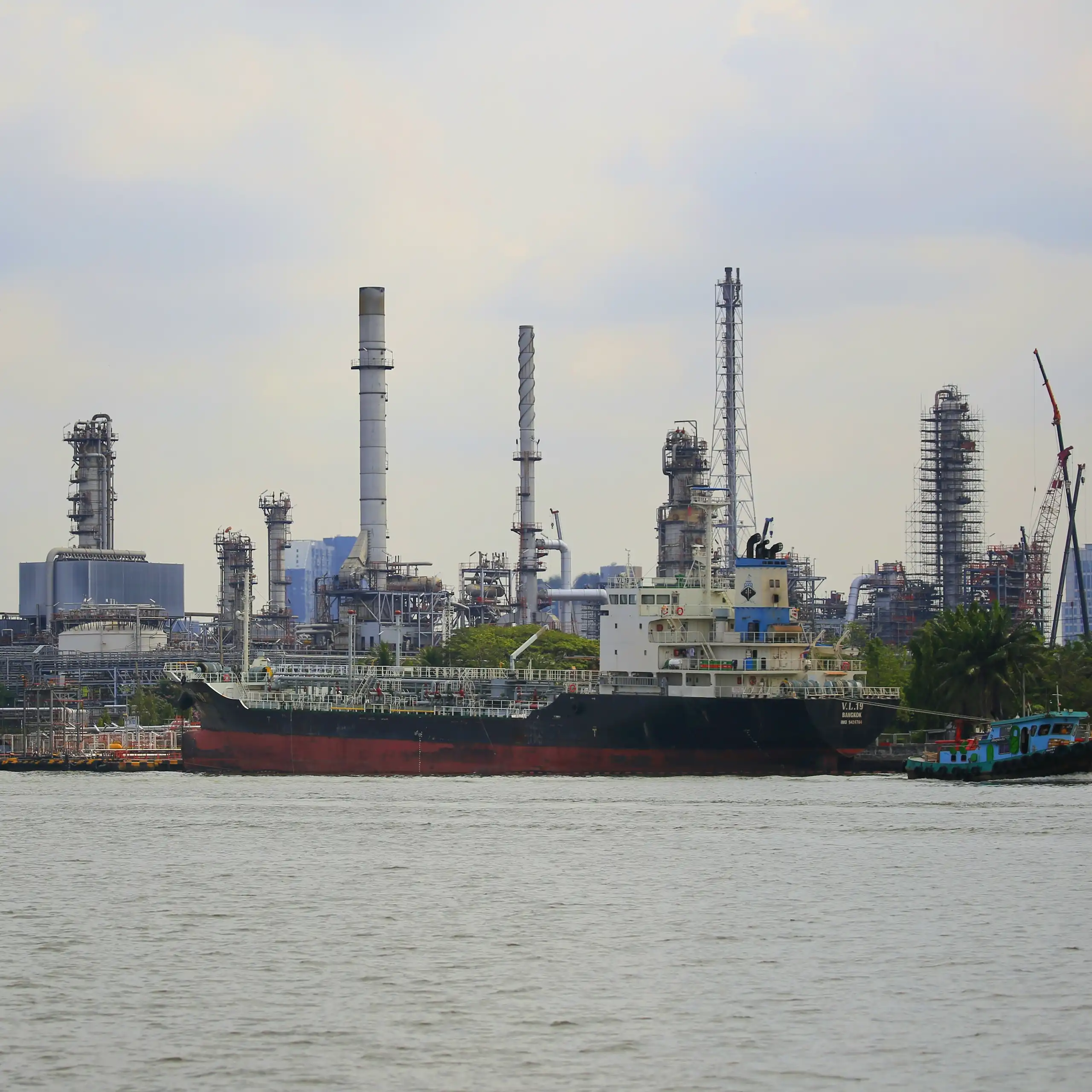 A large ship in the water with chimneys in the background