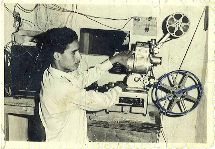 Un joven proyecta una película en un cine.