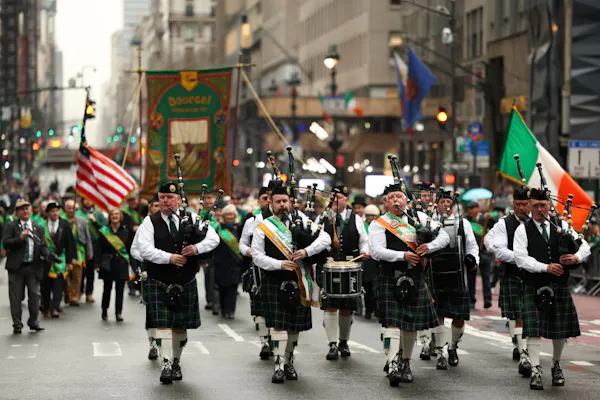 A group of bag pipers march down the street in a parade.