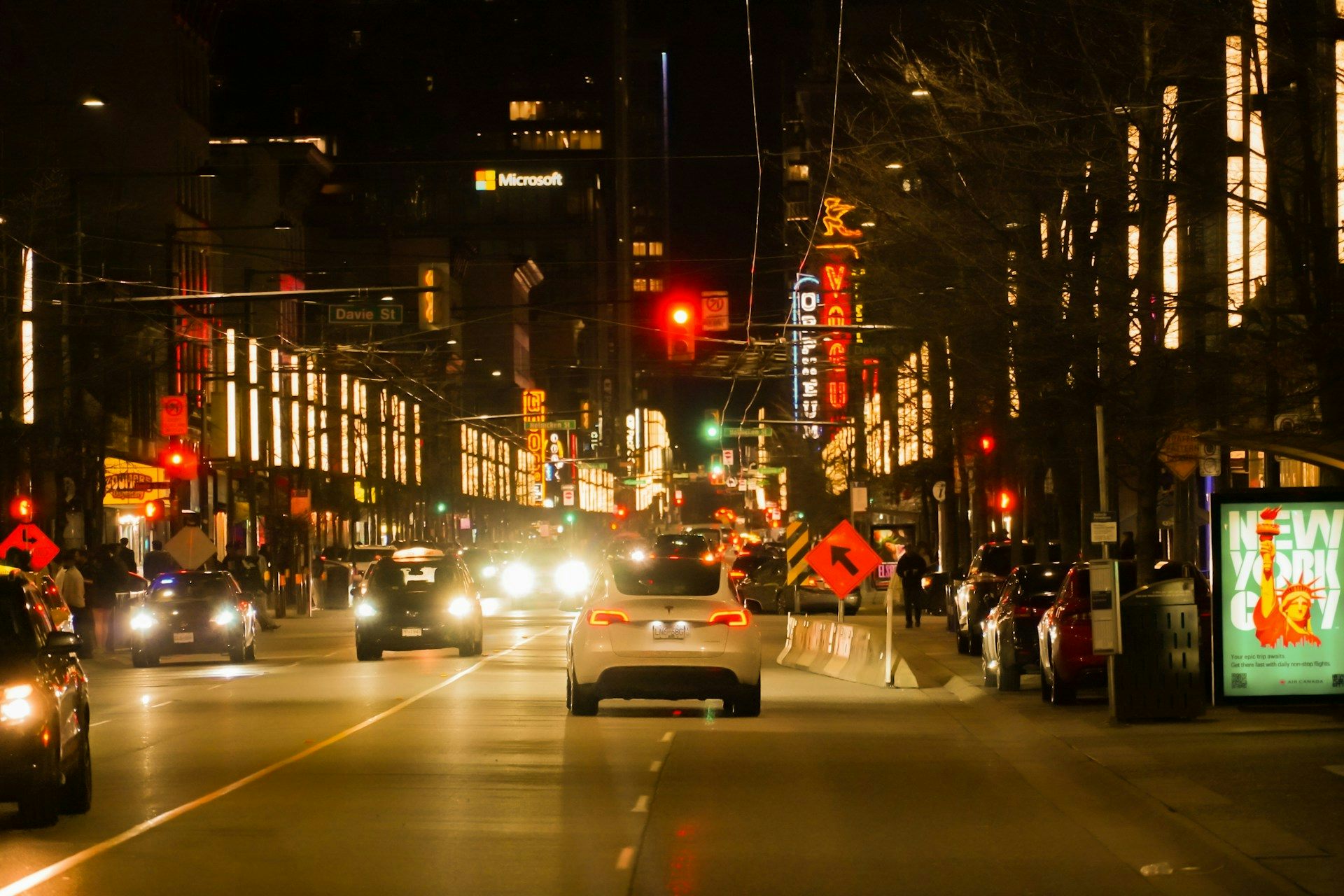 A car drives down a city street at night.