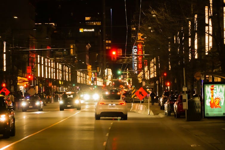 A car drives down a city street at night.