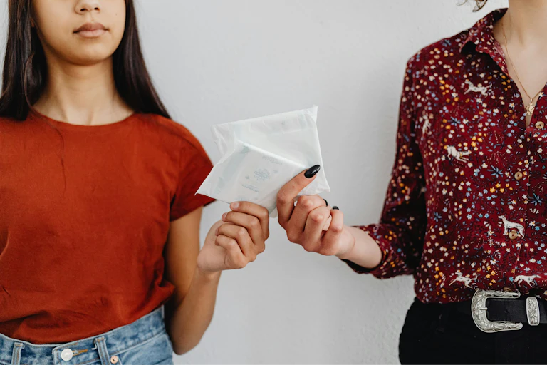 Two women exchange sanitary pads.
