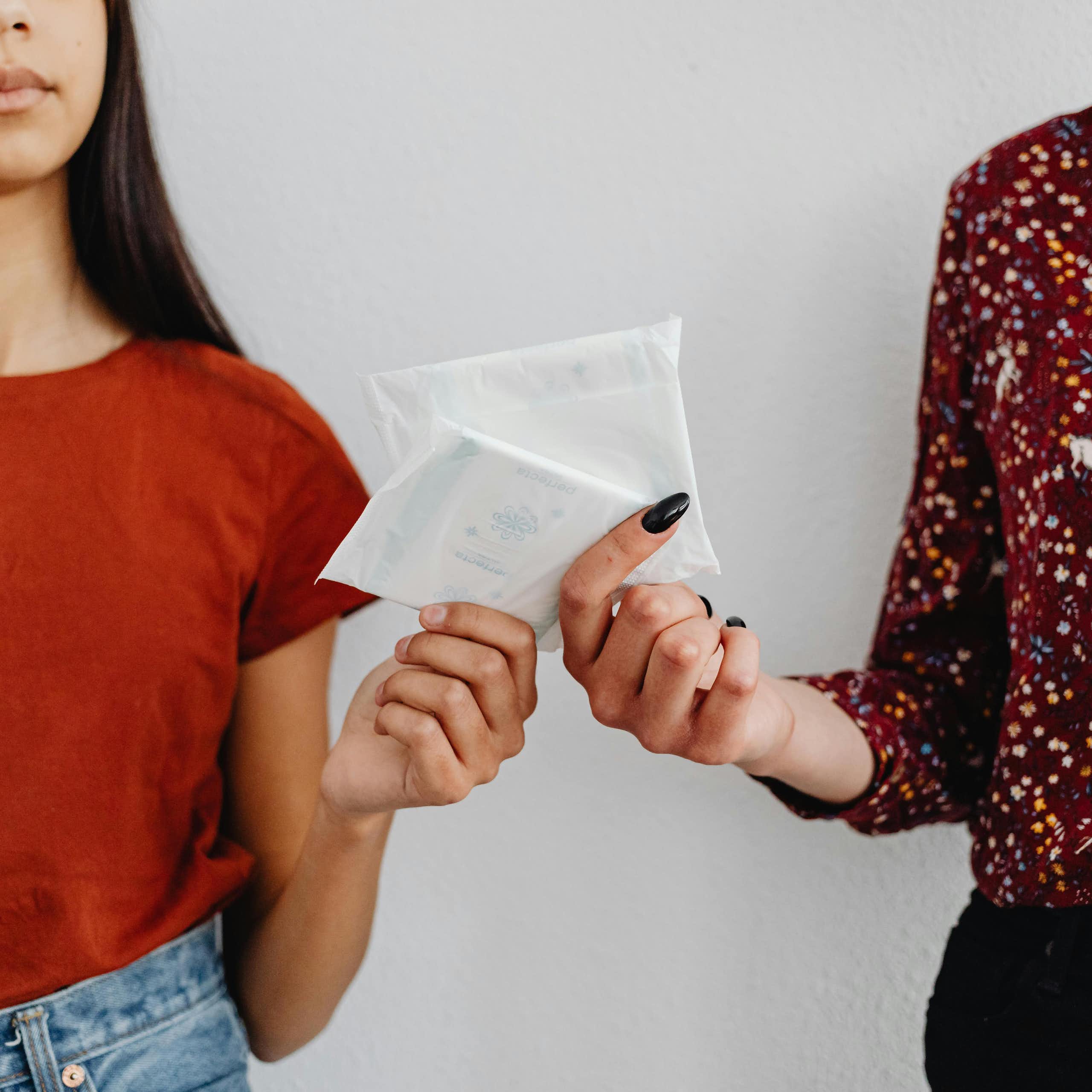 Two women exchange sanitary pads.