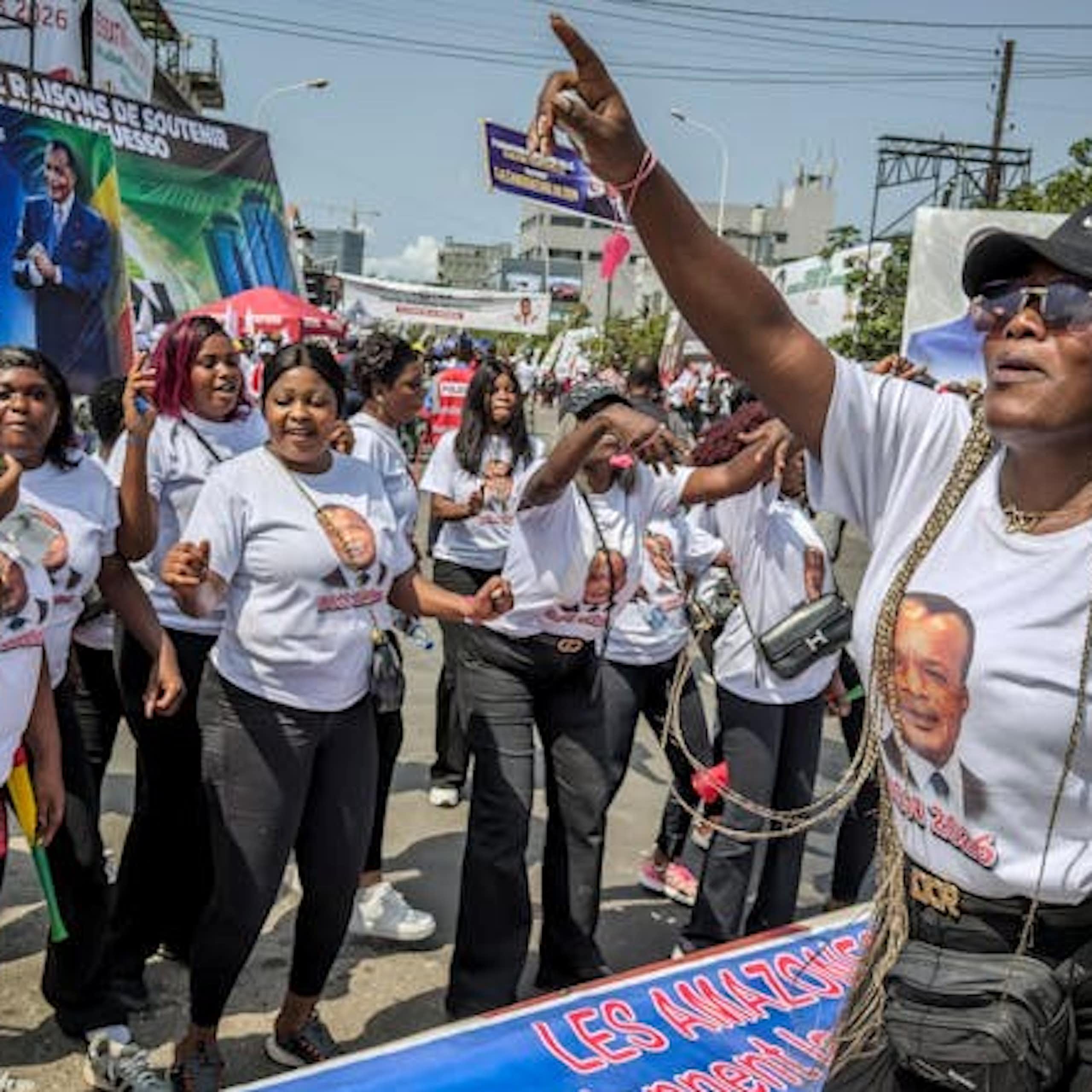 Women in a street, wearing T-shirts bearing a man's face