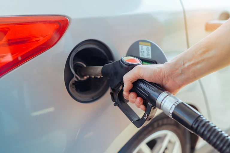 A hand on a pump as it fills a car with petrol.