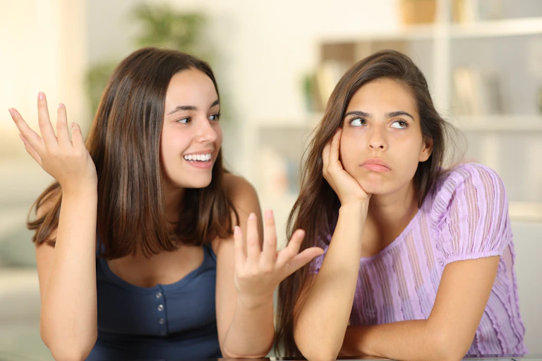 Two friends, one looking happy, the other, upset.