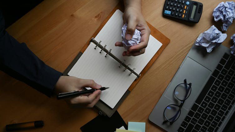 Fracaso: por qué los estudiantes de educación postsecundaria necesitan más espacio para cometer errores 1 Una mano arrugando papeles sobre una mesa.