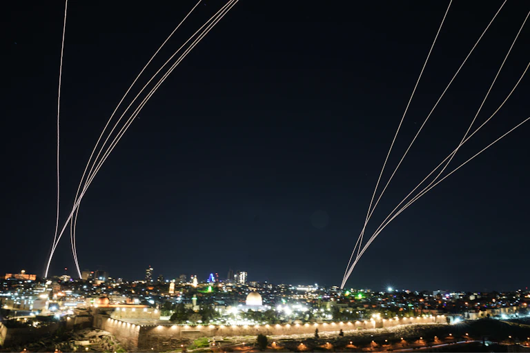 bright lines of light curve up into the night sky above a city