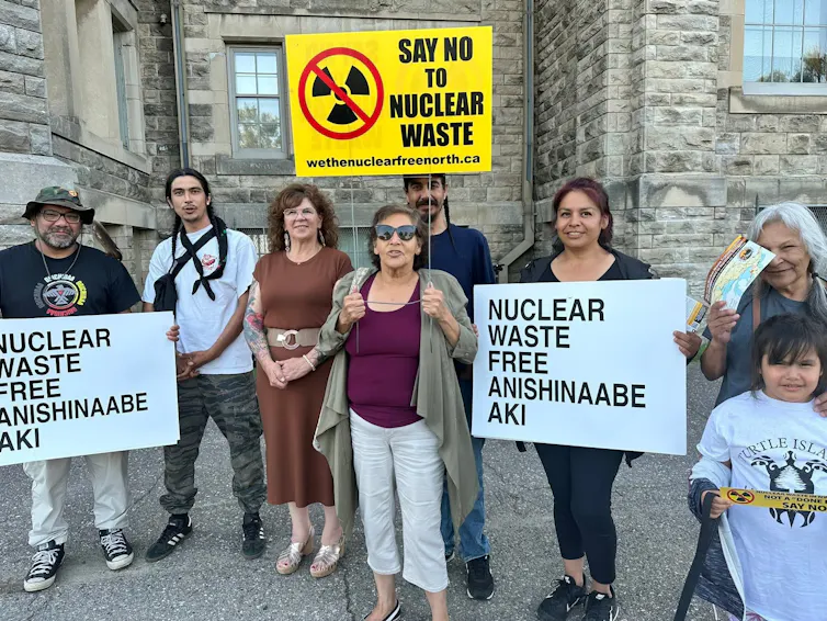 a group of people carry signs reading: say no to nuclear waste.